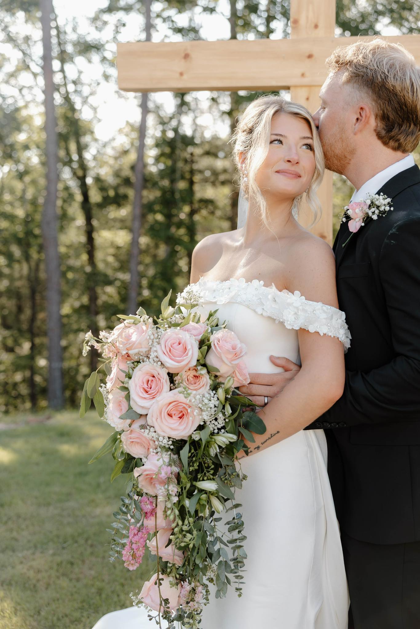bride and groom embracing in front of cross